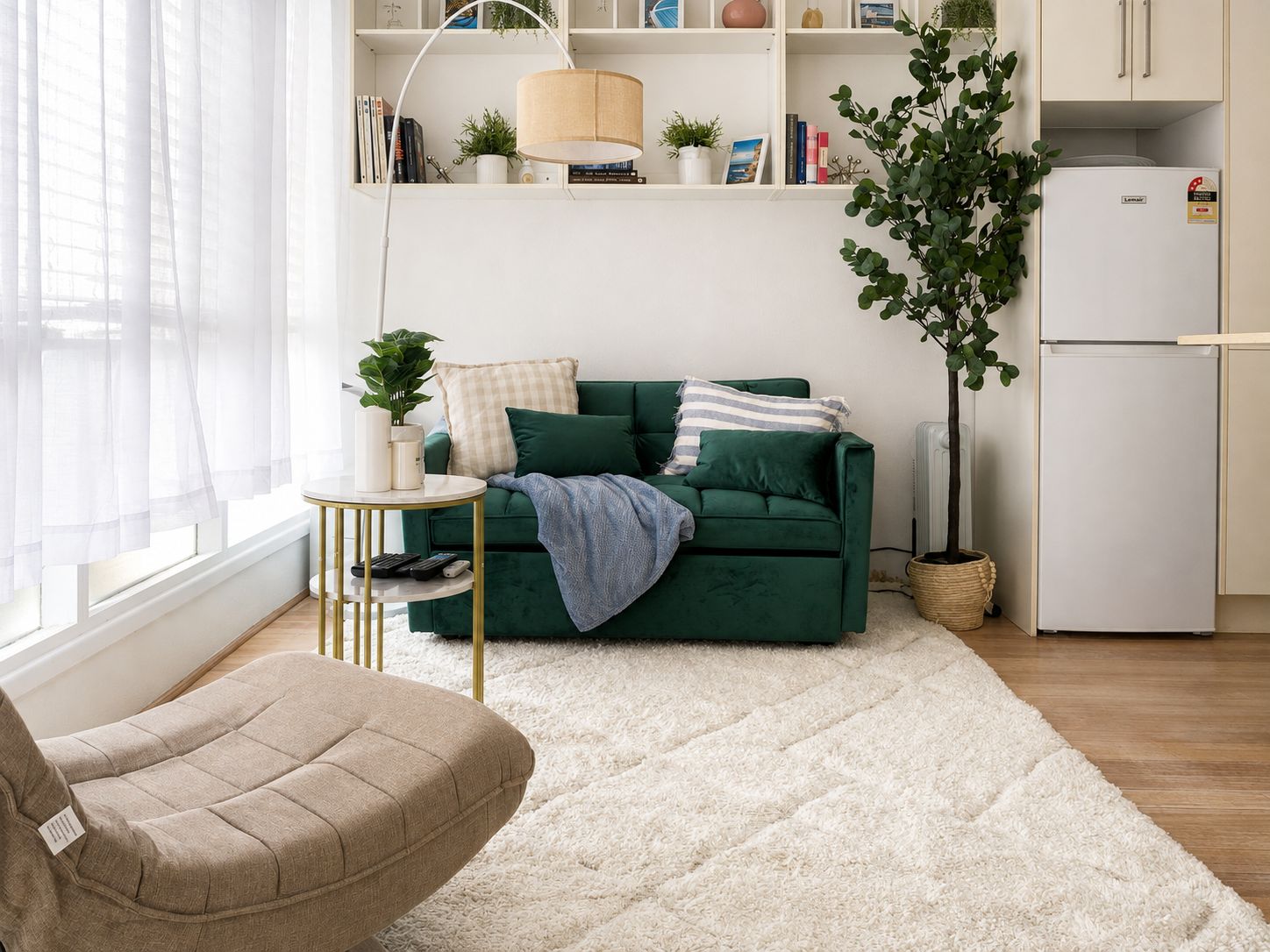 Una sala de estar moderna con un sofá verde, una mesa de centro redonda, un sillón beige, un radiador blanco y un refrigerador blanco.