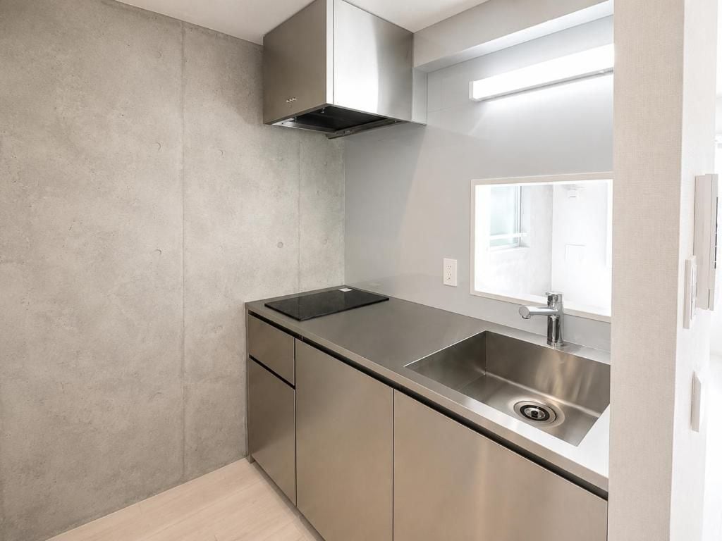 A compact kitchen with a stainless steel sink, a built-in oven, and a window above the sink.