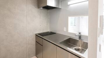 A compact kitchen with a stainless steel sink, a built-in oven, and a window above the sink.
