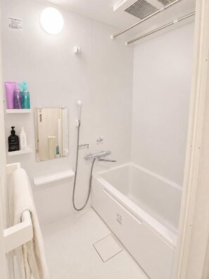 Un baño moderno con bañera, ducha y espejo.