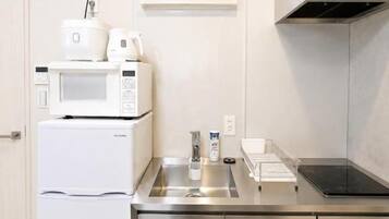 Eine moderne Küche mit Edelstahlgeräten, darunter eine Mikrowelle und ein Kühlschrank, sowie ein Spülbecken mit Armatur.
