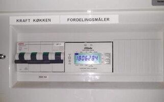 Ein Bedienfeld mit den Aufschriften 'KRAFT KØKKEN' und 'FORDELINGSMÅLER', das eine Küche und einen Verteilerzähler kennzeichnet.