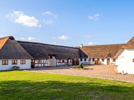 Ein traditionelles Gebäude mit Strohdächern und weißen Wänden, mit einem Innenhof mit Sitzgelegenheiten und einem kleinen Garten.