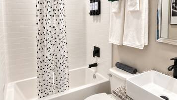 A bathroom with a bathtub, toilet, sink, and a shower curtain.