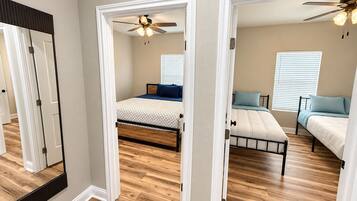 A bedroom with a bed, a ceiling fan, and a window with blinds.