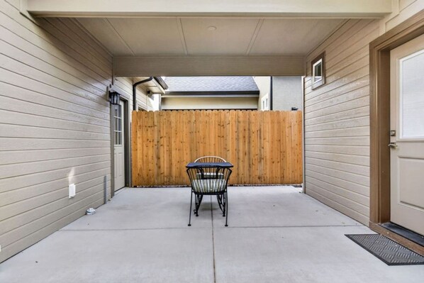 A covered patio with a table and chairs, a wooden fence, and a garage door. - Boise 1BR w/ Patio Near BSU, Downtown & Airport (Boise)