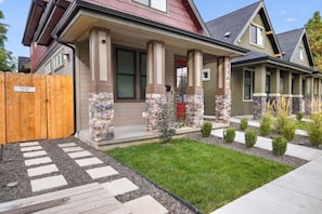 A residential house with a front porch, stone pillars, a well-maintained lawn, and a wooden fence. - Boise 1BR w/ Patio Near BSU, Downtown & Airport (Boise)
