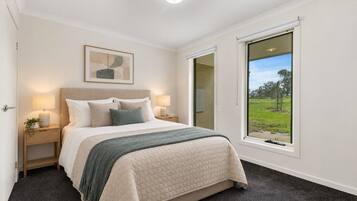 A bedroom with a bed, bedside tables, a window with a view, and a ceiling light.