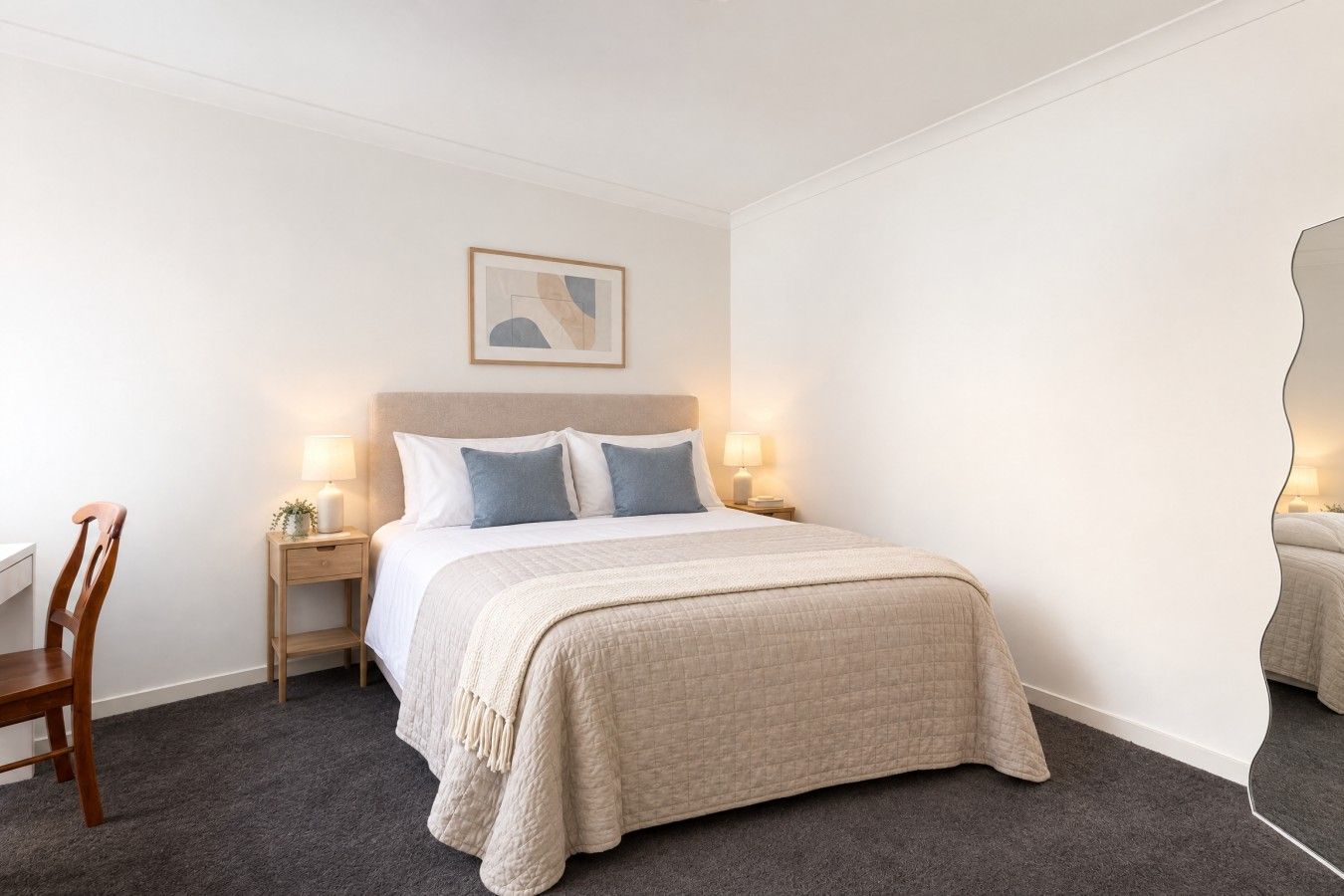 A hotel room with a bed, bedside tables, a chair, a framed picture on the wall, and a mirror.