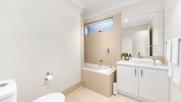 A modern bathroom with a toilet, sink, and bathtub.