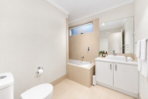 A modern bathroom with a toilet, sink, and bathtub. - Urban Pause on Flourish (Doreen)