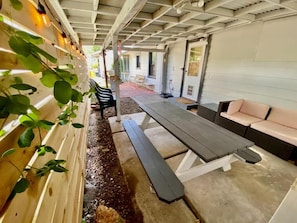 Un'area patio esterna con tavolo da picnic, panche e divano.