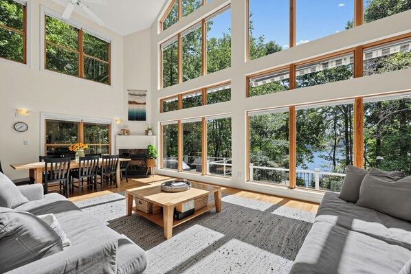A spacious living area with a large window overlooking a lake, a dining area with a table and chairs, and a sofa. - Lakefront retreat tucked among the trees above Lookout Shoals. (Stony Point)