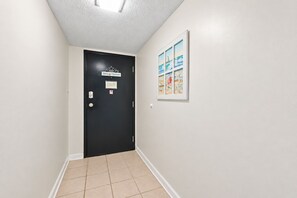 Ein Flur mit einer schwarzen Tür, einem gefliesten Boden und einem gerahmten Bild an der Wand.