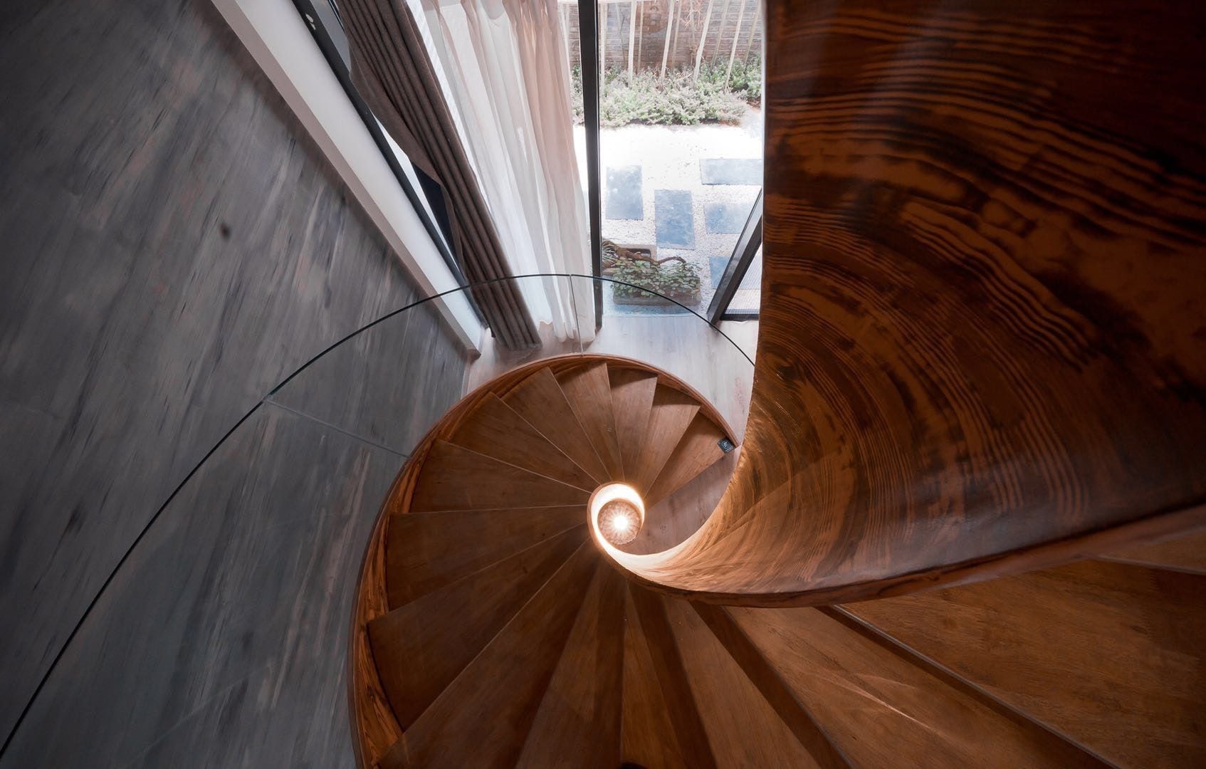 Una escalera en espiral con escalones de madera y un recinto de vidrio en la parte superior.