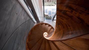 Una escalera en espiral con escalones de madera y un recinto de vidrio en la parte superior.