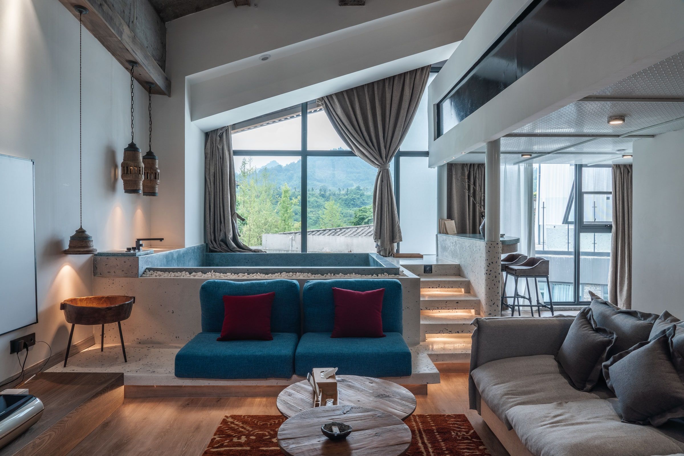 A modern living room with a large window, a built-in hot tub, and a seating area with sofas and a coffee table.