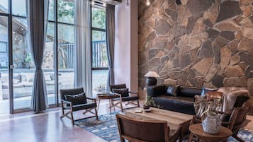 A modern interior with a stone wall, a sofa, chairs, a coffee table, and a view through large windows.