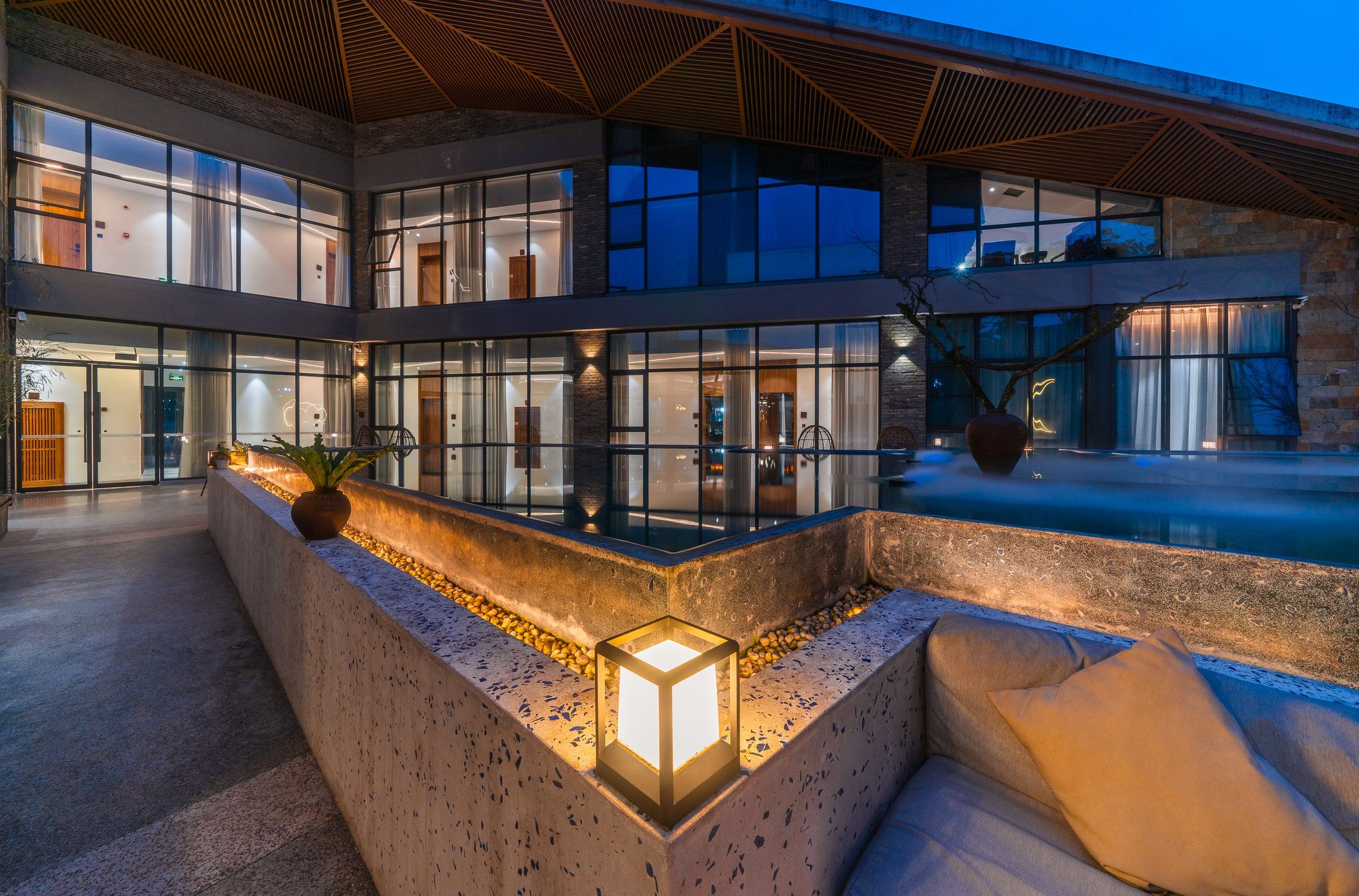 A modern building with multiple levels, large windows, and a pool area.