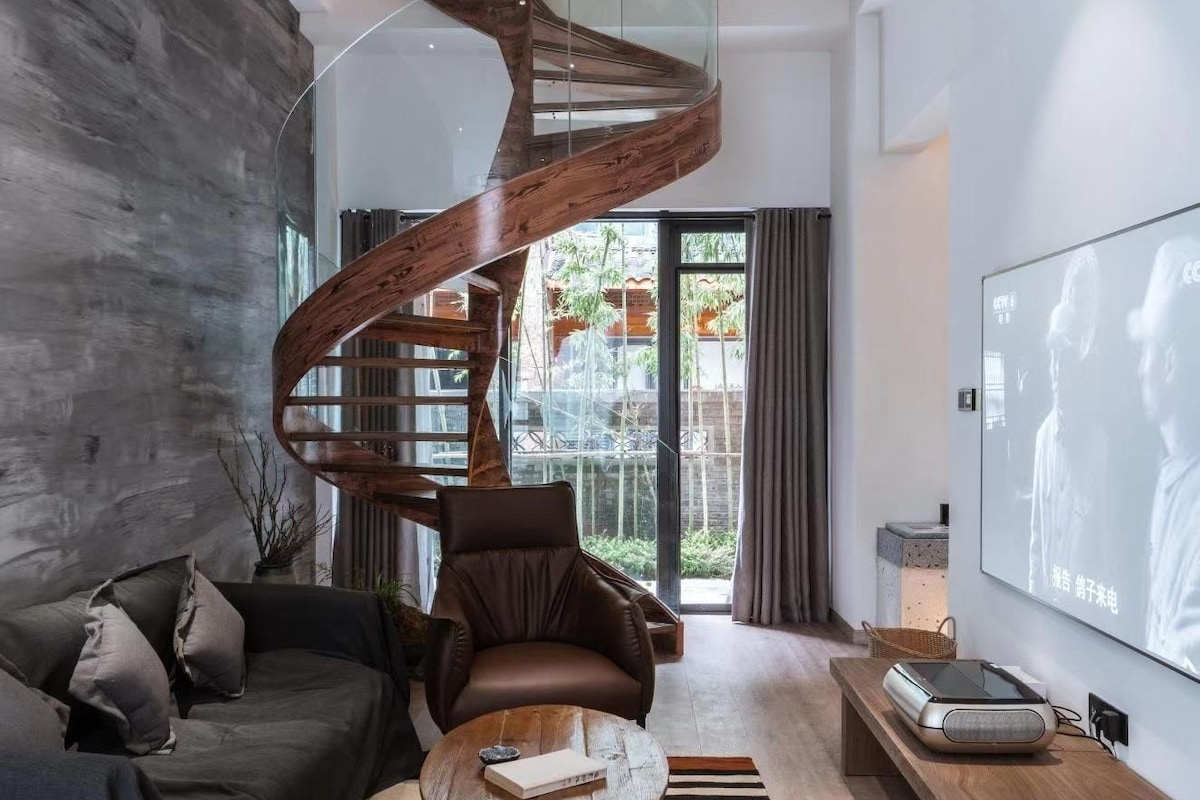 A modern living room with a curved wooden staircase, a leather sofa, a coffee table, and a flat-screen TV.