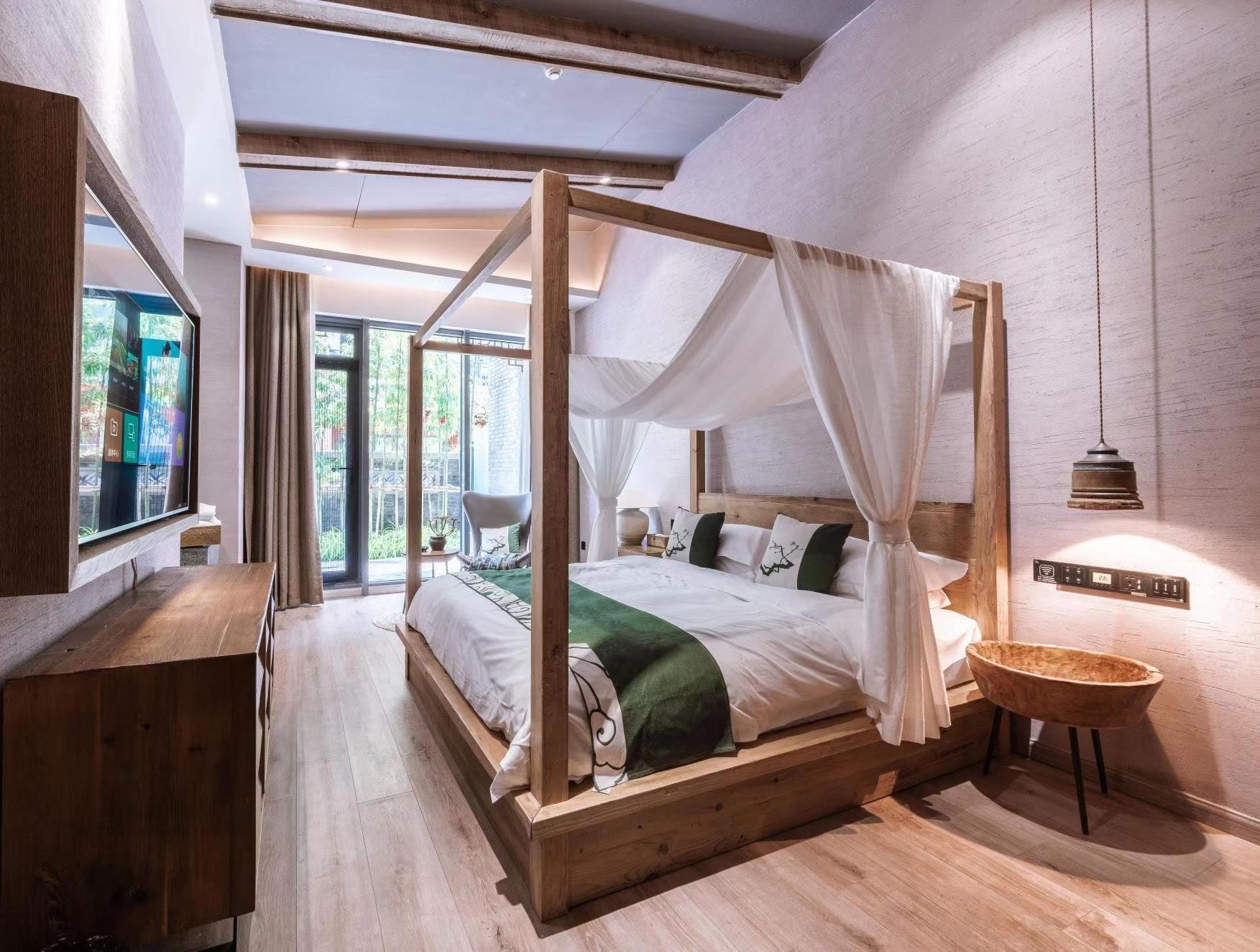 Una cama con dosel, una mesita de noche, una silla y una pequeña mesa redonda con una cesta.