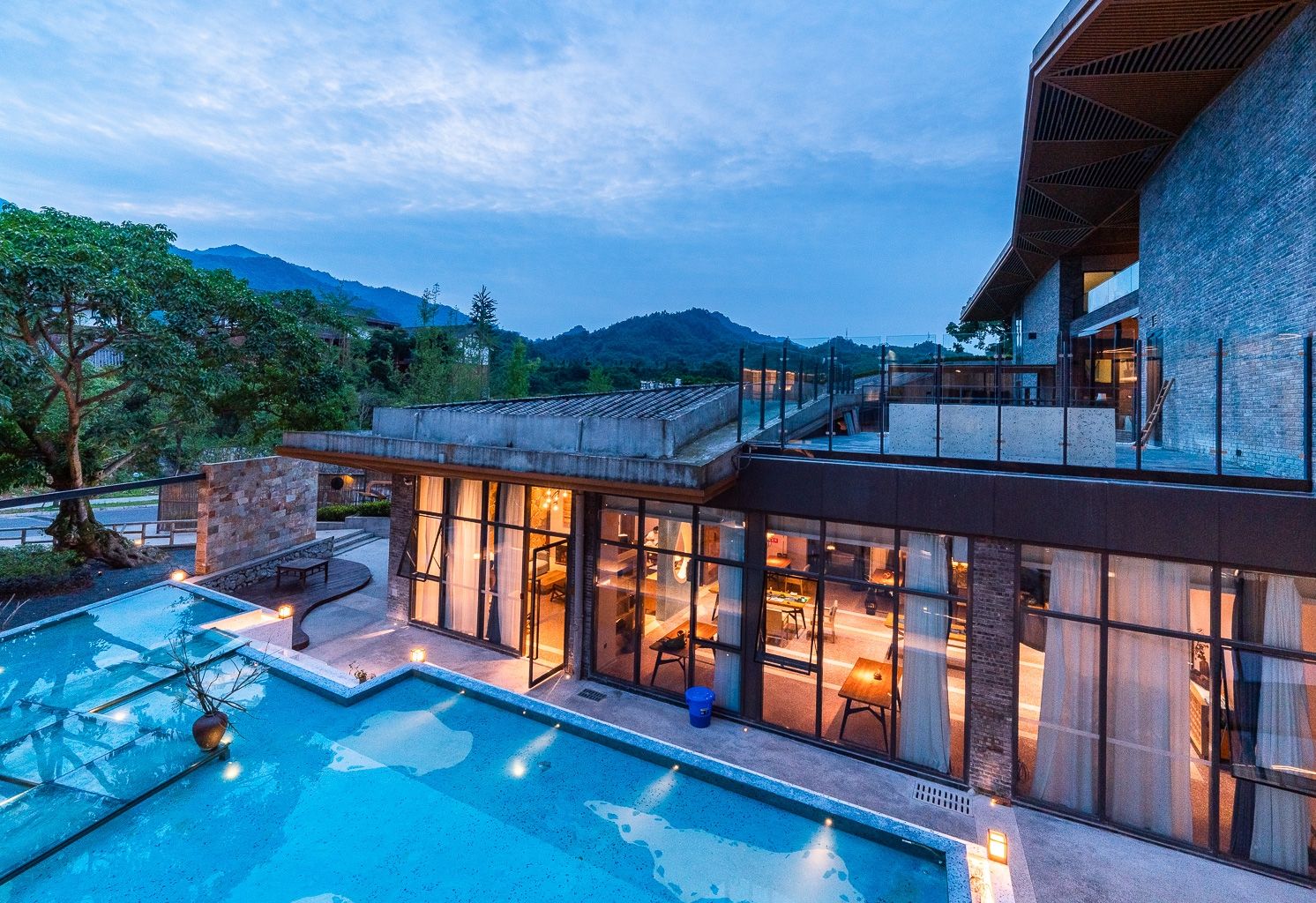 Una casa moderna con piscina, ventanas amplias y vistas a las montañas.