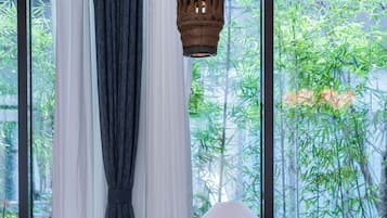 A room with a wooden table, a hanging lantern, and a view of bamboo outside.