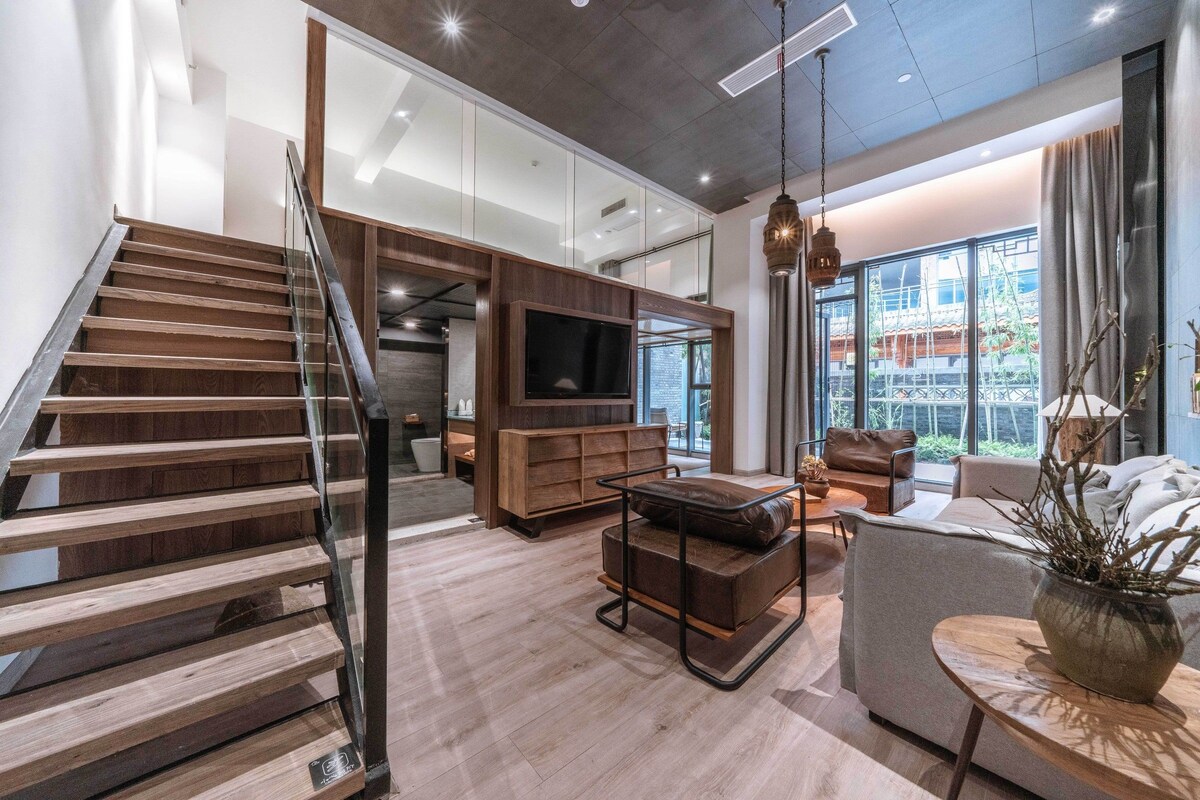 A modern interior with a staircase, a flat-screen TV, and a seating area with a view of the outdoors.