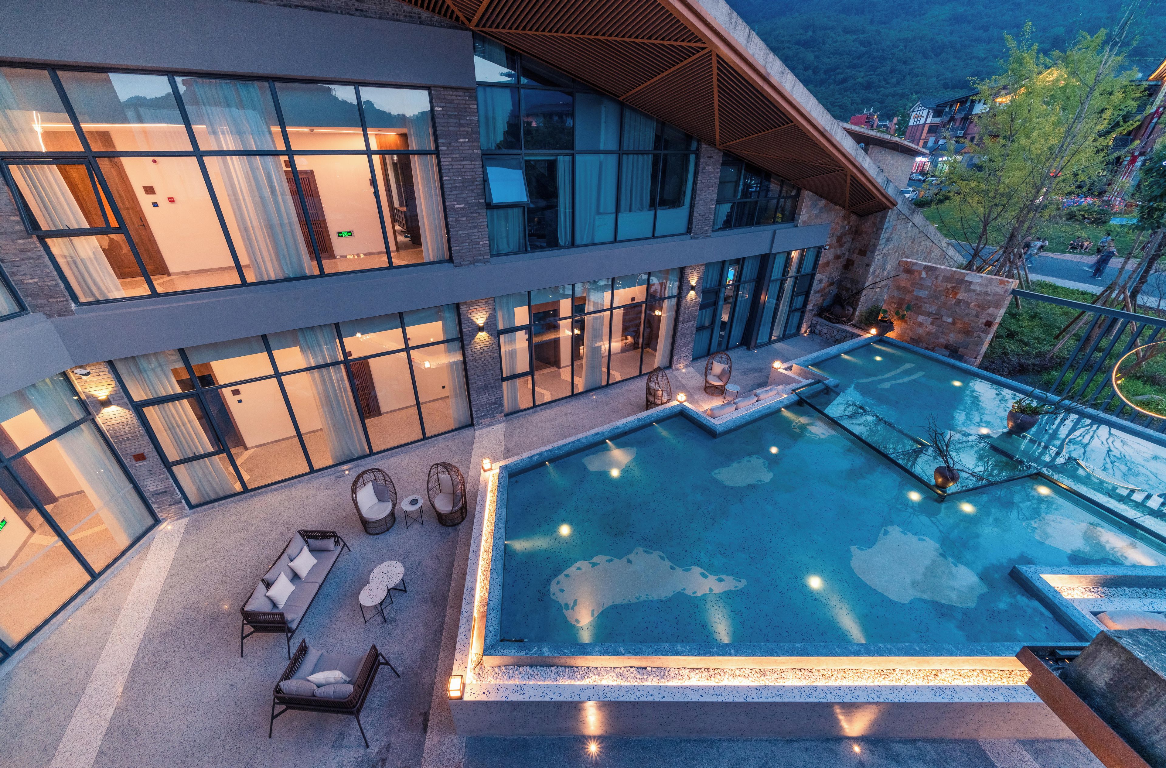 Un edificio moderno con piscina, asientos al aire libre y vistas del entorno.