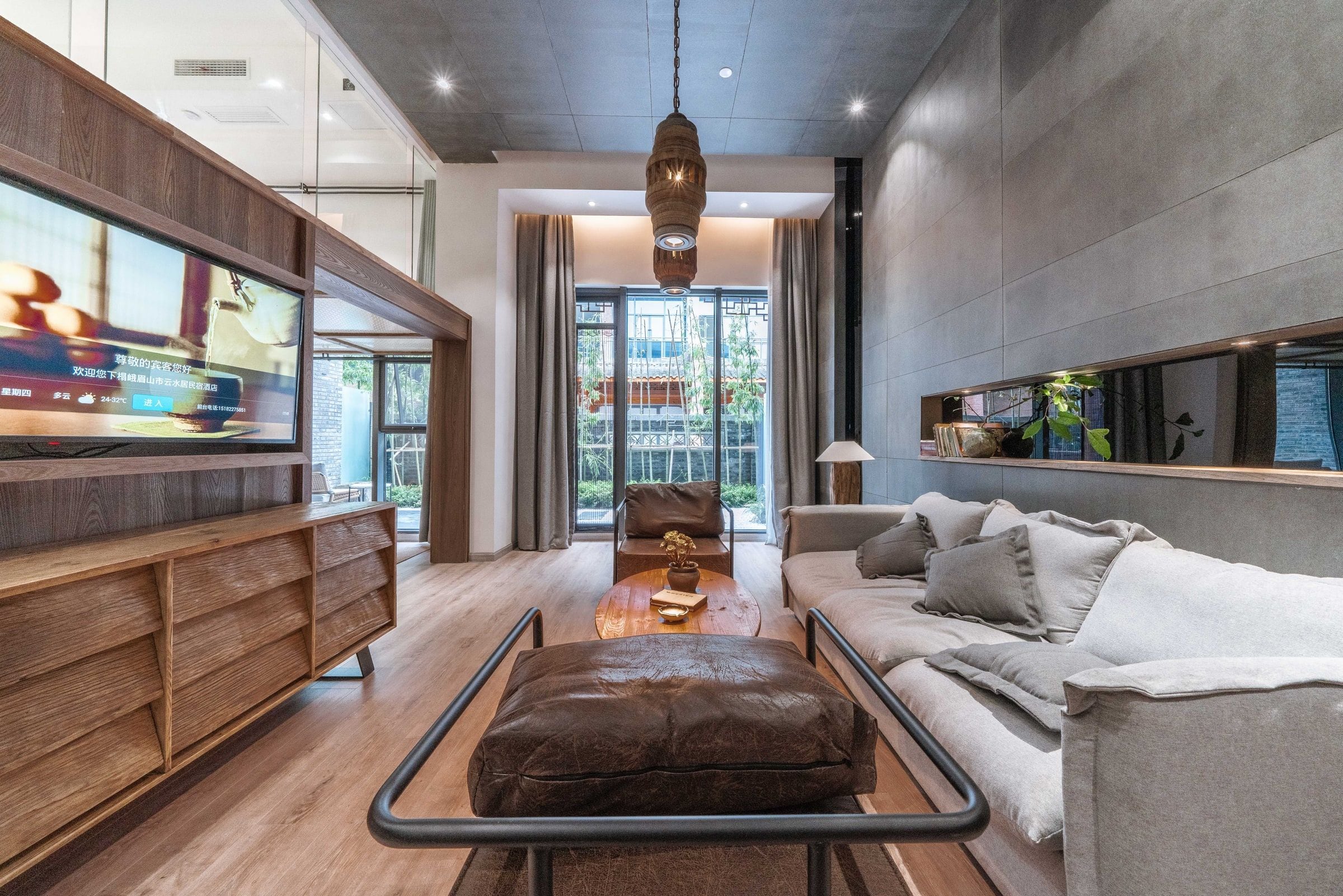 Una sala moderna con televisor, sofá, reposapiés y vistas al exterior.