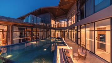 A modern hotel with a swimming pool, glass walls, and a rooftop terrace.