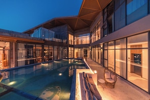 Un hotel moderno con piscina, paredes de vidrio y terraza en la azotea.