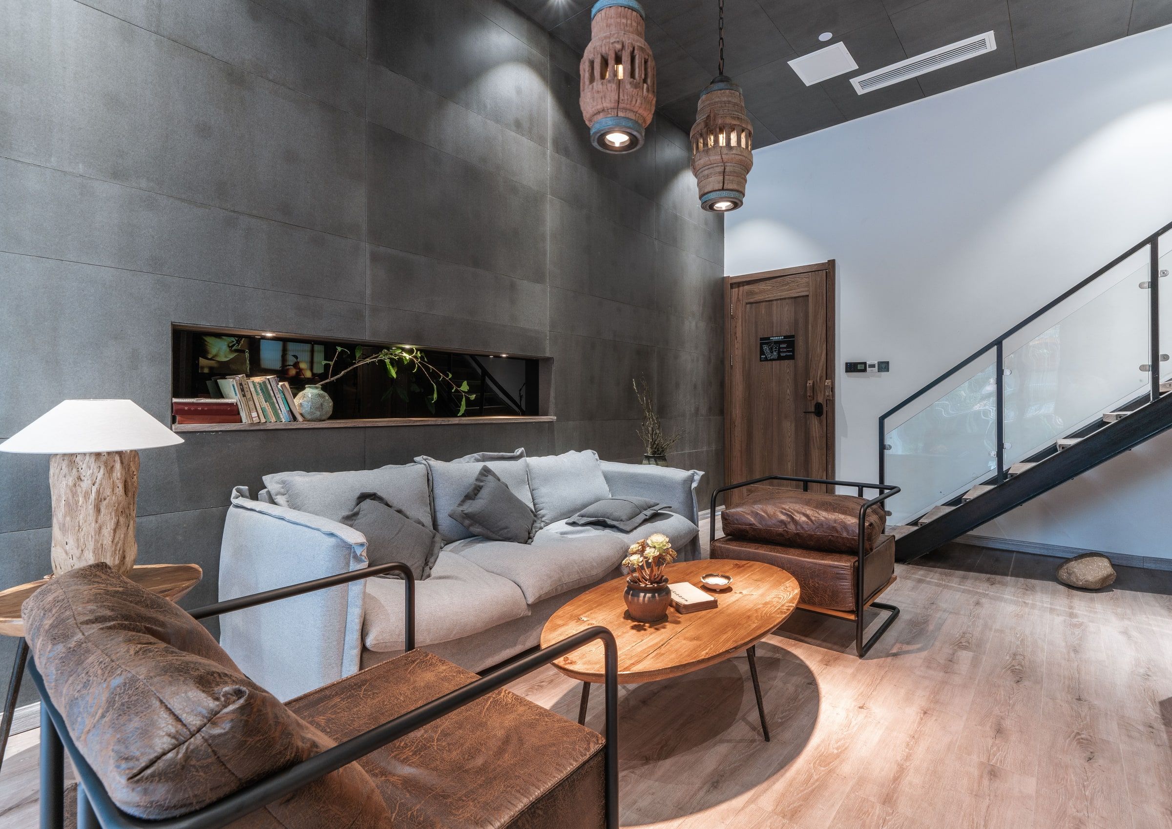 A modern interior with a grey sofa, wooden coffee table, and a staircase.