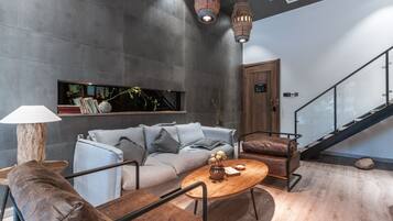 A modern interior with a grey sofa, wooden coffee table, and a staircase.