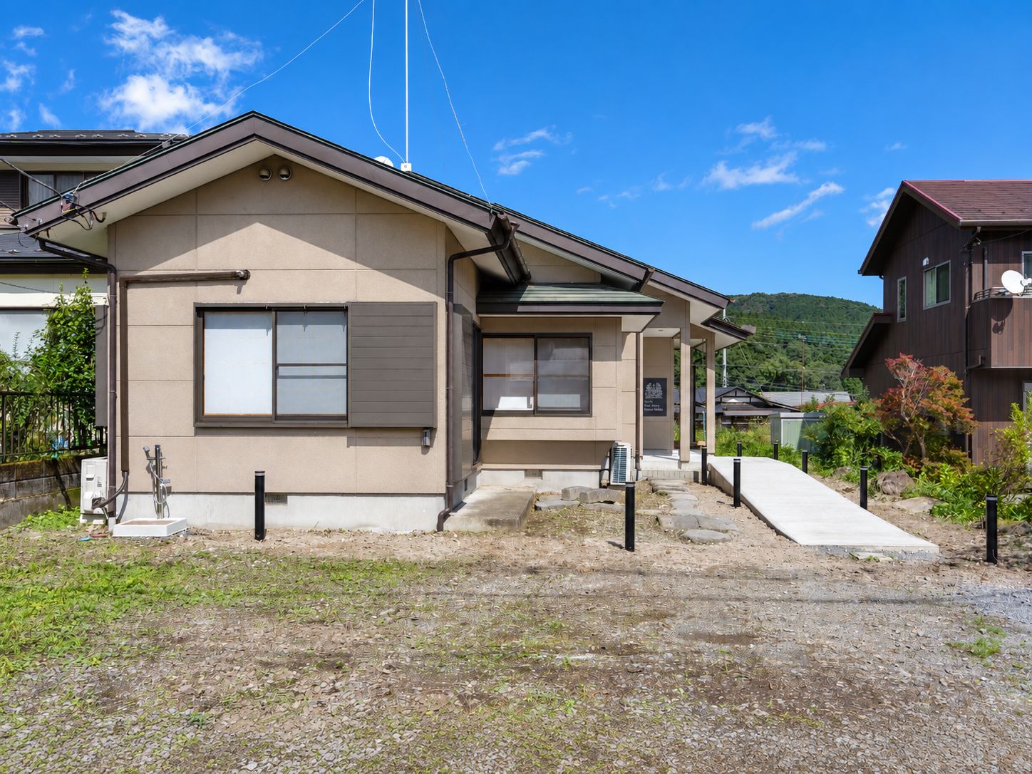 A residential building with a front porch, a small attached garage, and a paved driveway.