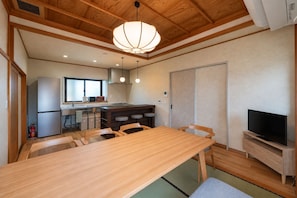 A compact kitchen with a dining area, a TV, and a wooden ceiling.