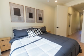Een slaapkamer met een bed, nachtkastjes en kunst aan de muur.