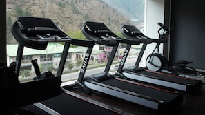 Tres cintas de correr en un gimnasio con vistas a un paisaje montañoso a través de un ventanal.