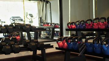 Una palestra con attrezzatura per sollevamento pesi, tra cui manubri e kettlebell.
