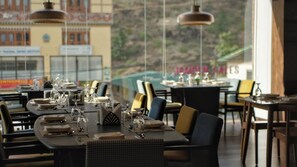 Un restaurante con mesas dispuestas para comer, con vistas a través de un ventanal grande.