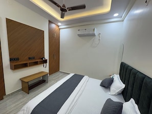 Une chambre à coucher moderne, équipée d’un lit, d’une table de chevet, d’une armoire, d’un ventilateur de plafond et d’un appareil de climatisation.