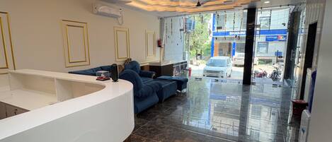 A reception area with a curved white counter, dark marble flooring, and a ceiling fan.