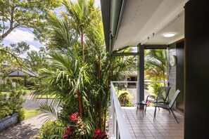 Een balkon met uitzicht op een tuin en een gebouw op de achtergrond.