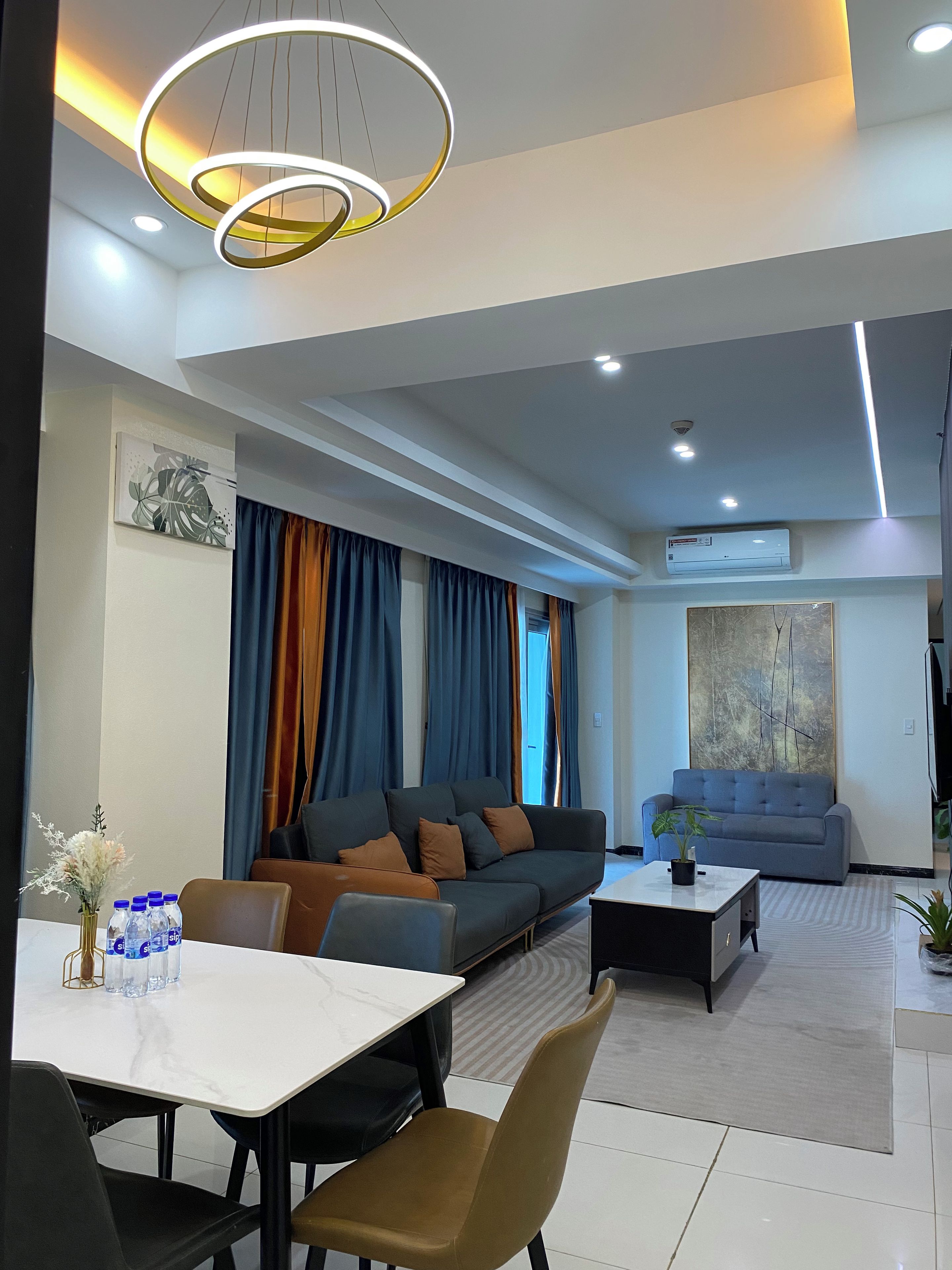 Una sala moderna con un sofá, una mesa de comedor con sillas y una mesa auxiliar.
