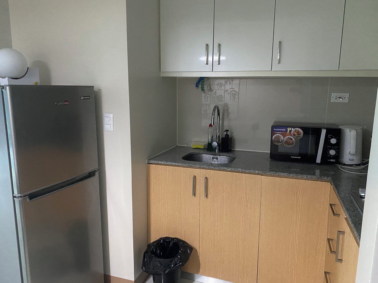 A compact kitchen with a refrigerator, microwave, and sink.