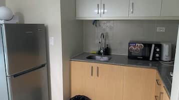 A compact kitchen with a refrigerator, microwave, and sink.
