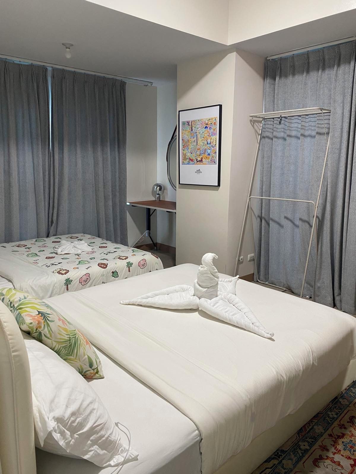 Habitación de hotel con dos camas, zona de ducha, toallero y un cuadro enmarcado en la pared.
