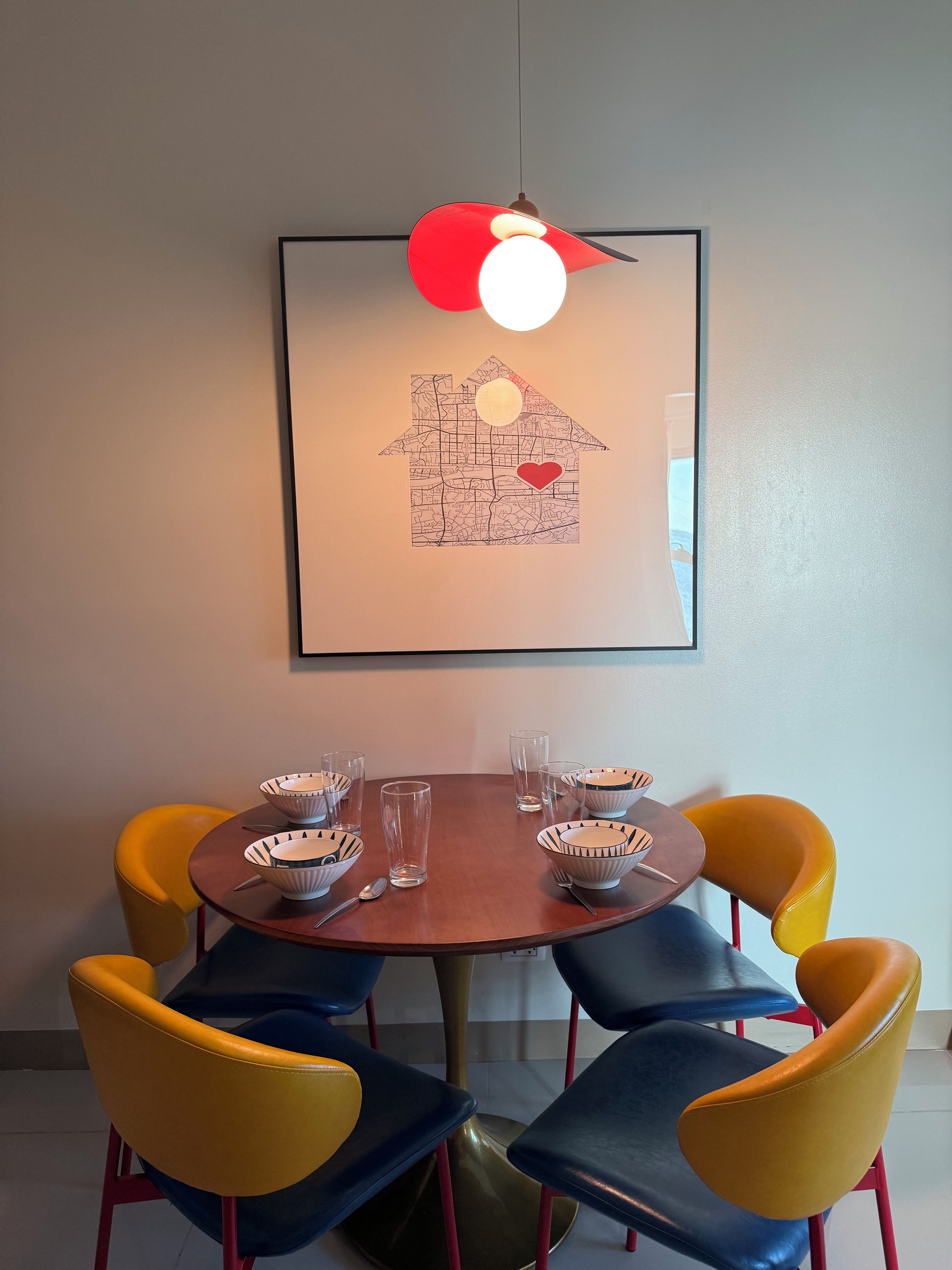 A dining area with a round table, six chairs, and a framed map on the wall.