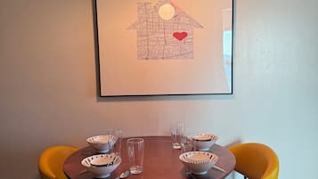 A dining area with a round table, six chairs, and a framed map on the wall.