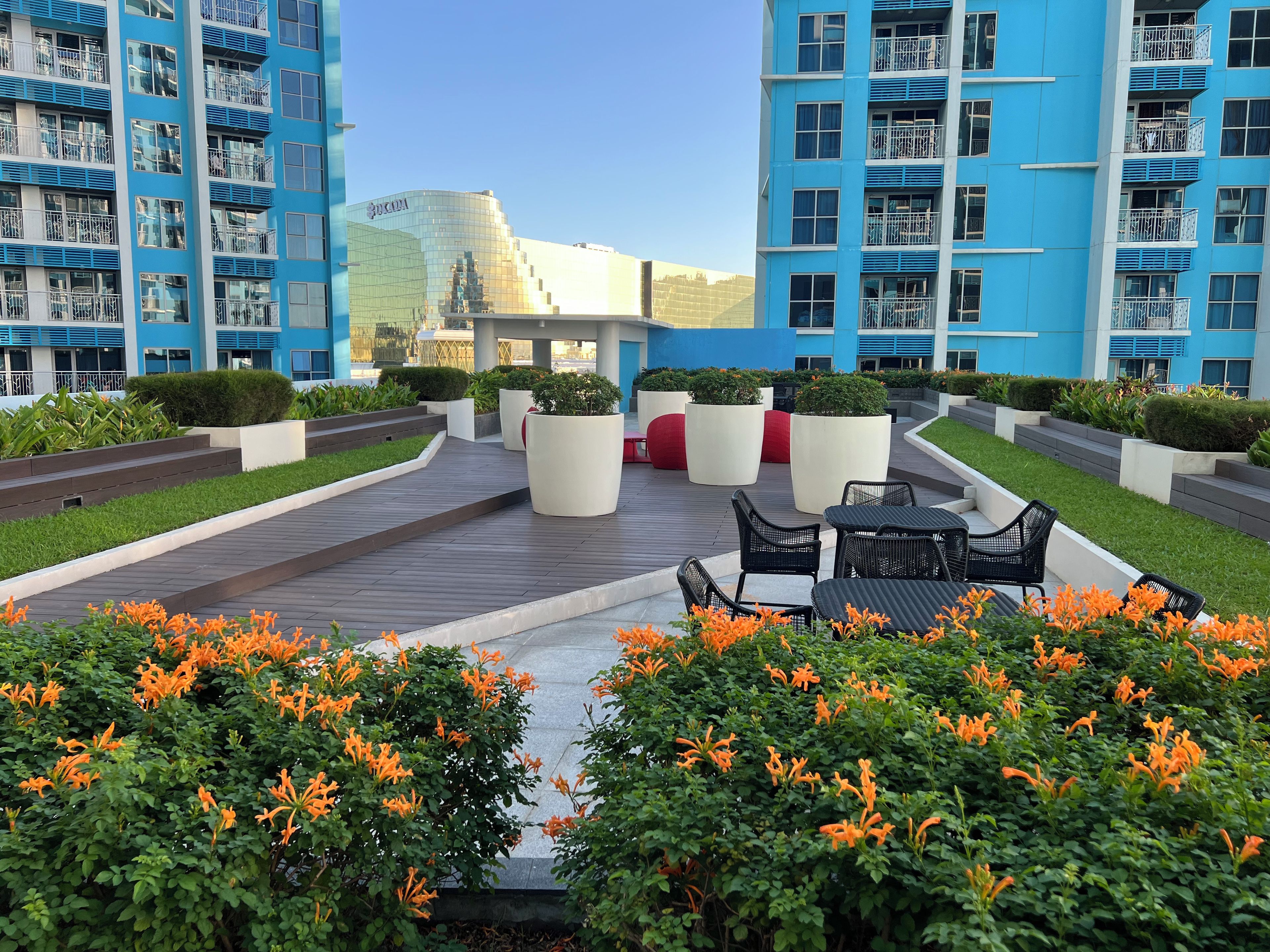 Un hotel moderno con jardín en la azotea, asientos exteriores y vistas a un paisaje urbano.